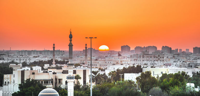 Zonsondergang met oranje lucht boven de stad Muscat, Oman