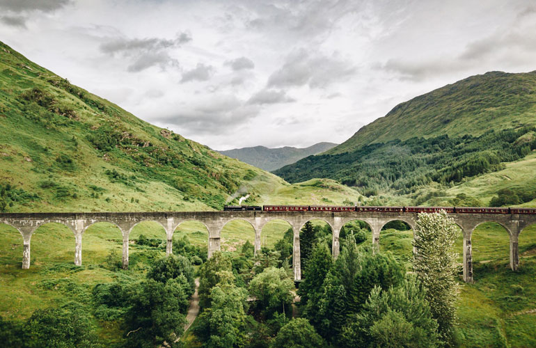 Trein die over de Glenfinnan-viaduct in de Schotse Hooglanden rijdt, met bergen op de achtergrond