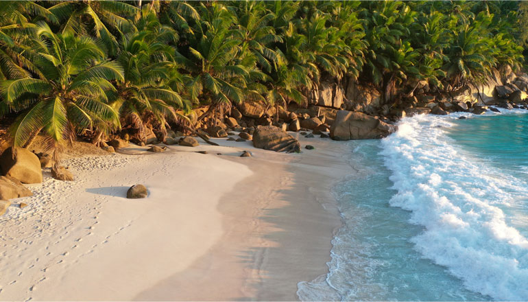 Golven die tijdens zonsondergang op de kustlijn van de Seychellen beuken